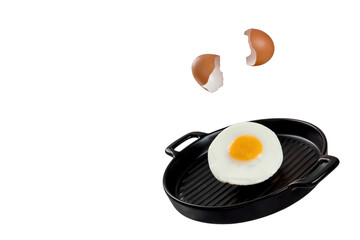 Levitating fried egg and shells on a black ceramic pan. 