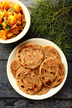 North Indian recipes- homemade wheat paratha, porota, porotta with spicy cooked aloo paneer dish. healthy vegetarian cuisine.