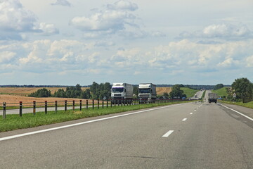 European heavy trucks into oncoming traffic lane move on the countryside highway road at Sunny...