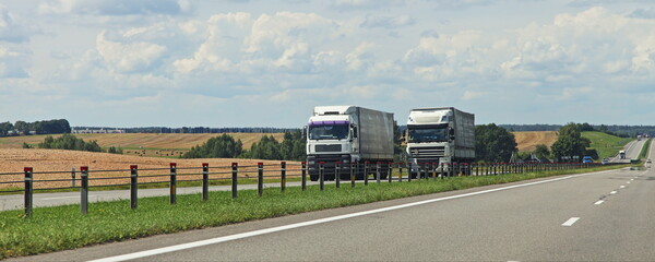 European heavy trucks into oncoming traffic lane on the countryside highway road motion at Sunny...
