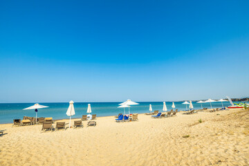 Fototapeta na wymiar Beautiful landscape view of empty sunbeds and umbrellas on sand beach. Greece.