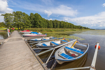 Beautiful view of lake with boats parked in shore on blue sky background.  Sweden.