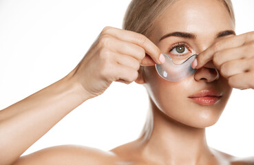 Indoor shot of calm relaxed woman has fresh healthy skin, wears collagen patches under eyes, gets...