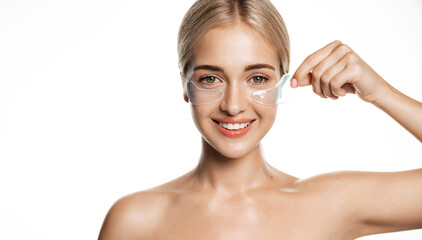 Cosmetic procedures. Beautiful young woman taking off under eye patches for puffiness, smiling...