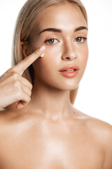 Close up beauty girl with thick eyebrows, applying moisturizing skincare cream, lotion or mask for...