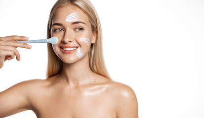 Skin care and wellbeing. Young blond girl using cosmetic makeup brush for facial cream, lotion or face mask for better skin without acne, white background