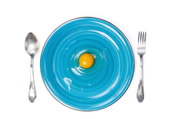 Egg yolk on blue plate with table setting, top view. Isolated on white.