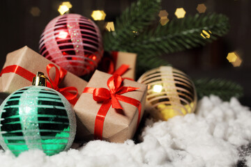 Christmas gifts next to Christmas balls, against the background of flashing lights of a garland in out-of-focus