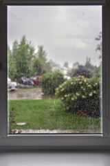 Rainy day view from the window, raindrops on glass, blurred cloudy rainy sky background