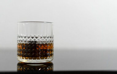 Whiskey with whiskey stones. A glass of whiskey in a crystal glass with whiskey stones in front of a brown background