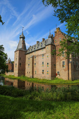 Obraz premium View beyond green trees on dutch water castle from 14th century against blue summer sky