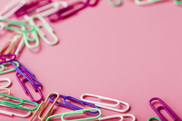 Multicolored rzhivtkzhtsrbt Paper clips scattered on a pink background