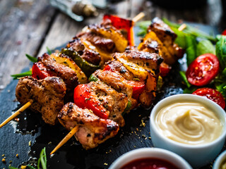 Skewers - grilled meat with fresh vegetables on wooden background
