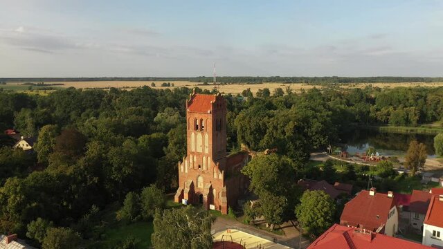 Aerial: The restored facades of the Zheleznodorozhny town on the background of an abandoned old Prussian church, Russia