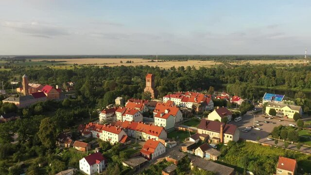 Aerial: The restored facades of the Zheleznodorozhny town on the background of an abandoned old Prussian church, Russia