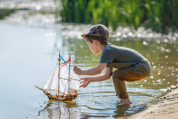 little boy in cap launching ship on the river