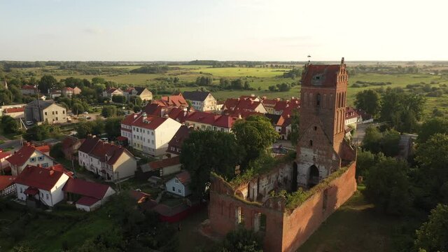 Aerial: The restored facades of the Zheleznodorozhny town on the background of an abandoned old Prussian church, Russia