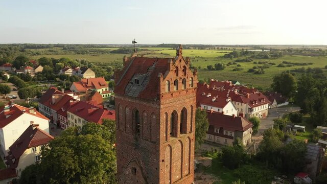 Aerial: The restored facades of the Zheleznodorozhny town on the background of an abandoned old Prussian church, Russia