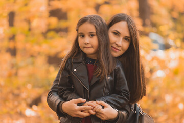 Little girl playing with mother in the autumn park