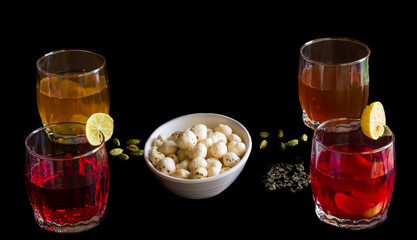 Front view of crunchy Fox Nuts also called Makhana or Makhane or Lotus Seeds.Served with Sangria fruit punch made from Kokam juice,Kashmiri Kahwa green tea on dark background. Indian summer drink. 