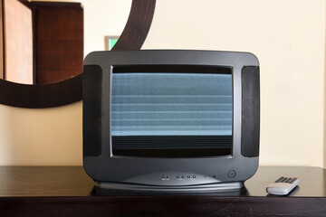 An old black TV with noise on the screen sits on the bedside table in the apartment. Vintage TVs...