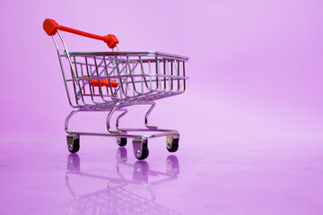A small supermarket trolley on a light purple background.