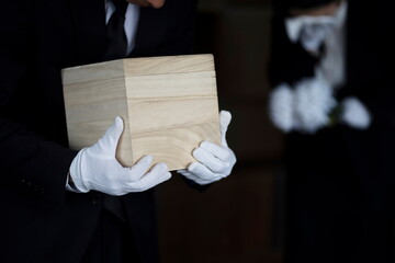Bereaved holding urn at funeral - obrazy, fototapety, plakaty
