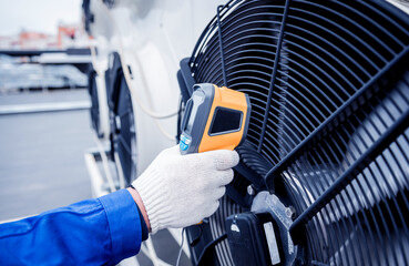 Technician uses a thermal imaging infrared thermometer to check the condensing unit heat exchanger.