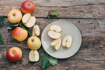 Red apples are lying on a plate and a wooden table. Harvest season, cooking at home, autumn food