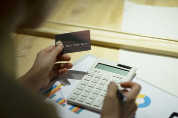 Fototapeta premium Woman using calculator with credit card 