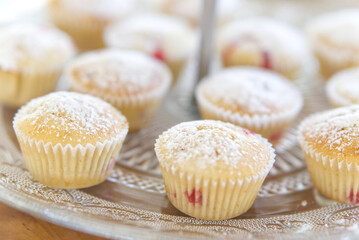 Muffins mit roten Beeren und Puderzucker auf einem Glasteller