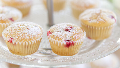 Muffin mit roten Johannisbeeren und Puderzucker auf einem Glasteller