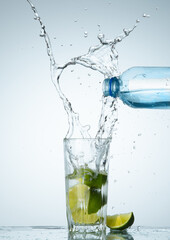 Water pouring from bottle into the glass with lemon