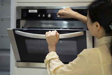Fototapeta na wymiar Woman using oven in kitchen