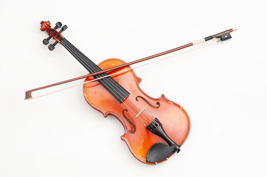 A violin with a bow on a white wooden background. A musical stringed instrument.