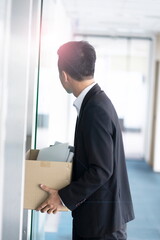 Fired businessman leaving office with box of belongs