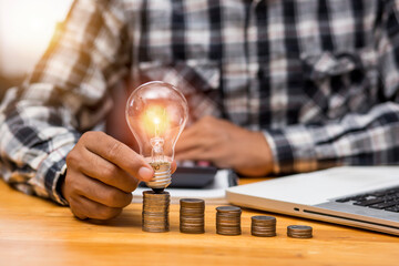 Business man holding light bulb on the Green background nature and writing on note book it for 