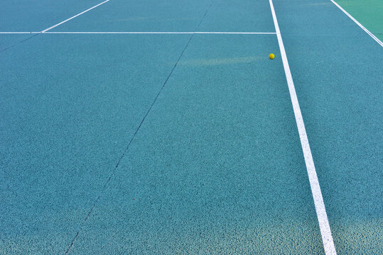 Terrain de tennis en Quick bleu et sa balle jaune égarée