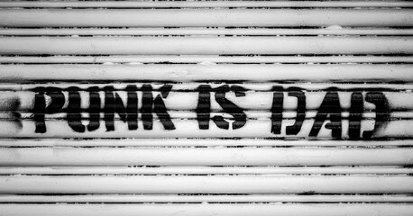 The message Punk Is Dad has been spray stencilled onto a grunge wall