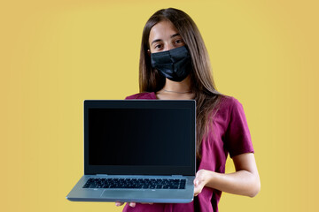 Young caucasian girl with portable pc computer isolated yellow background. Perfect template for cyber monday, promo messages and advertising. Mask on face. Adapt for back to school and websites