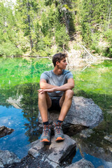 Young caucasian boy relaxing of a lake during a mountain trekking. Adventurous trip, vacations, exploring, water, t-shirt