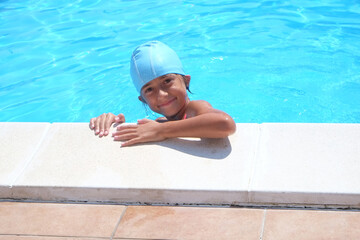 Little girl learn to swim in a pool during summer in Italy. Cute, young, children, swimming, sport, water, swimming cap