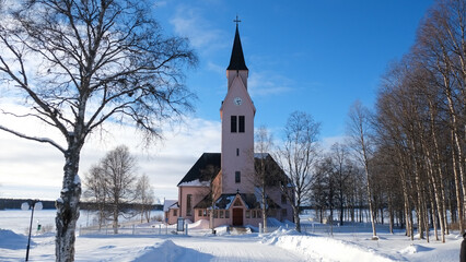 Fototapeta na wymiar Beautiful church in Sweden during a sunny day with snow in winter season. Perfect Christmas background. Quiet and peaceful landscape.
