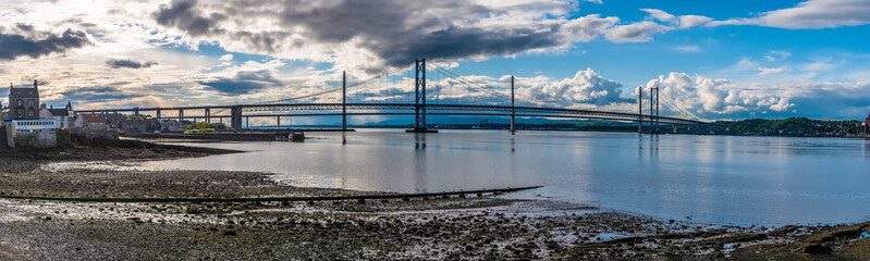 A panorama view along the shore at Queensferry towards the road bridges over the Firth of Forth, Scotland on a summers day
