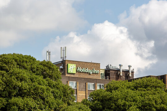 08-12-2021 Portsmouth, Hampshire, UK The Sign of Holiday Inn hotel through trees