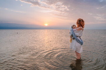 Young woman mother with red hair holding her baby standing outdoor