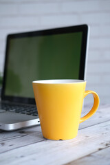 yellow color coffee mug and laptop a on table 