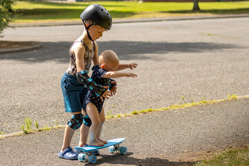 older brother teaches baby to skate