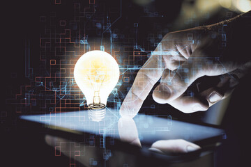 Double exposure of man's hands holding and using a digital device and bulb hologram drawing. Idea concept.