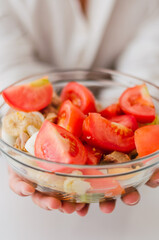 Close-up of young handsome Chinese man eating a fresh, delicious and healthy tomate salad with tune on the sofa in the living room of a minimalist and clean home